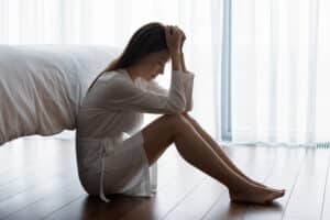 emotional distressed woman sitting on bedroom floor