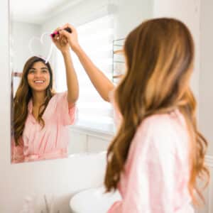 woman drawing heart on bathroom mirror